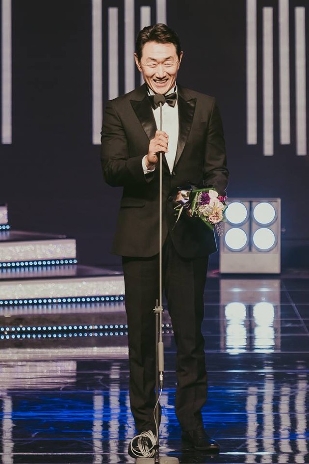 Gambar Foto Heo Joon Ho terlihat tertawa bahagia saat memenangkan trofi KDA Award.